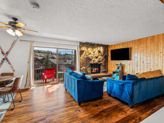 Step into this cozy living space, featuring a stunning stone fireplace and a modern flat-screen TV.