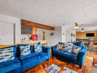 Step into this cozy living space, featuring plush blue sofas and a unique wooden coffee table.