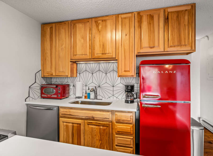 This charming kitchen features beautiful wooden cabinets, a stylish backsplash, and a modern stainless steel dishwasher.