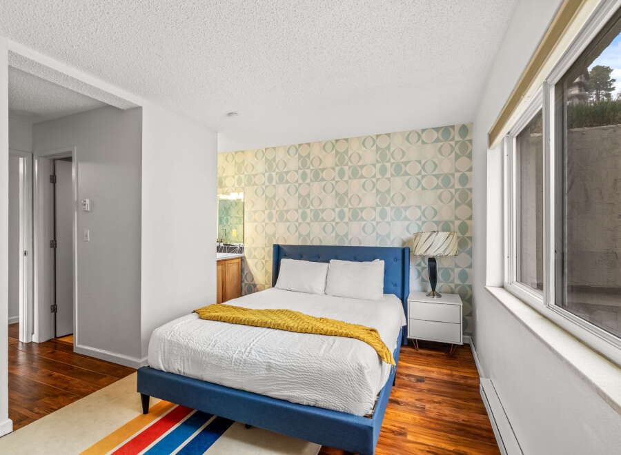 This charming bedroom features a stylish blue bed frame and a vibrant patterned accent wall, creating a cozy and inviting atmosphere.