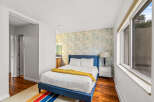 This charming bedroom features a stylish blue bed frame and a vibrant patterned accent wall, creating a cozy and inviting atmosphere.