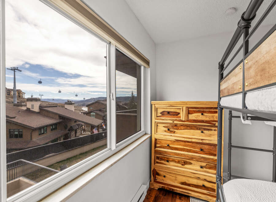 Enjoy stunning mountain views from this cozy bedroom! This space features a beautiful wooden dresser and a stylish bunk bed, perfect for a vacation rental or a family home.
