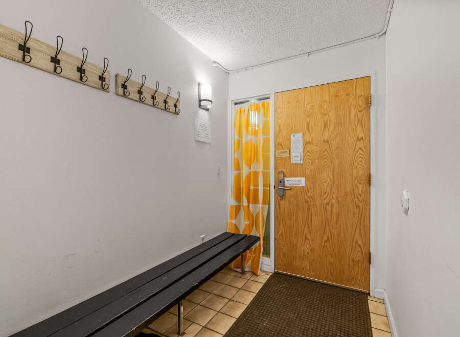 This entryway features a welcoming atmosphere with a wooden door and a stylish bench.