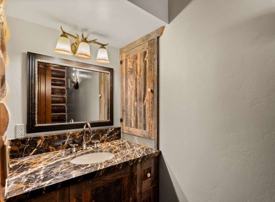 This stunning bathroom features a rustic design with a beautiful marble countertop and a wooden vanity.