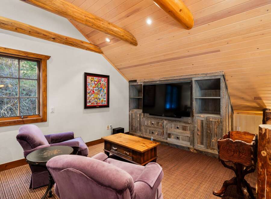 This cozy living space features a rustic aesthetic with wooden beams and a paneled ceiling.