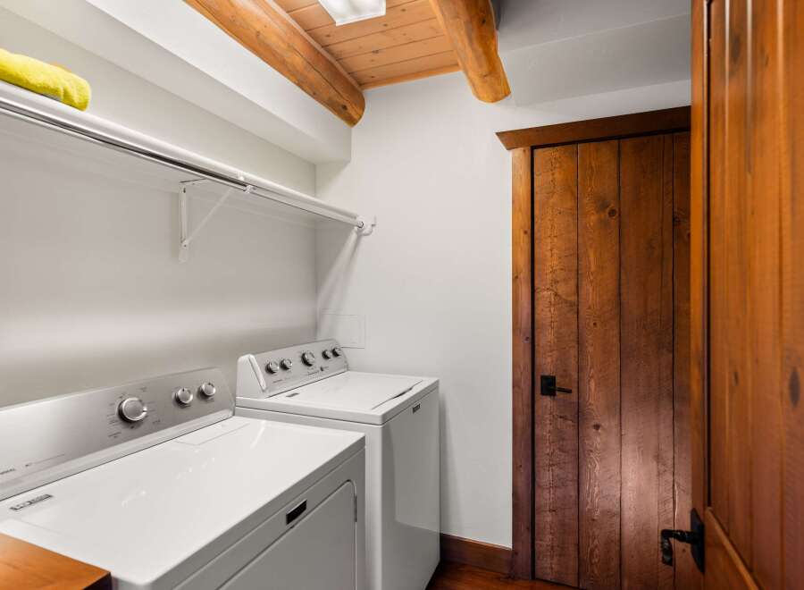 This laundry room boasts a rustic charm with its wooden door and ceiling beams, creating a warm and inviting atmosphere.