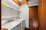 This laundry room boasts a rustic charm with its wooden door and ceiling beams, creating a warm and inviting atmosphere.