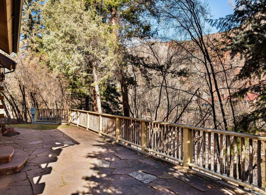 Enjoy the tranquility of this stunning property with a beautiful stone patio and a charming wooden railing.