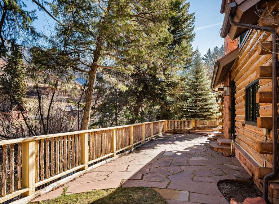 Enjoy the tranquility of this stunning property featuring a beautiful stone patio and a charming log cabin exterior.