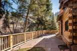 Enjoy the tranquility of this stunning property featuring a beautiful stone patio and a charming log cabin exterior.