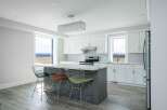 This stunning kitchen boasts a modern design with sleek white cabinetry and a spacious island, perfect for both cooking and entertaining.