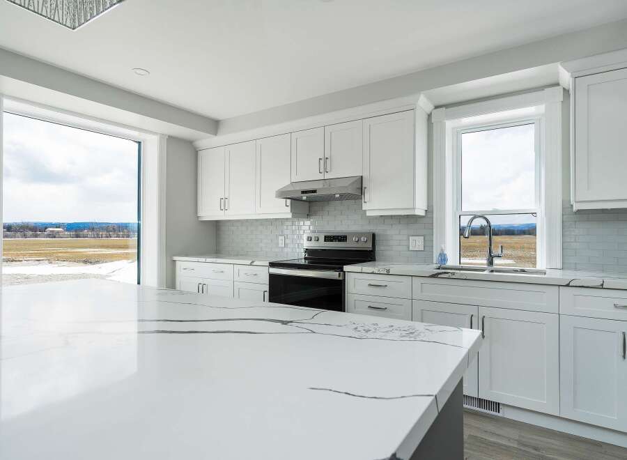 This stunning kitchen boasts a modern design with sleek white cabinetry and a spacious island, perfect for culinary enthusiasts.