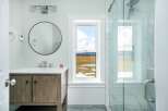 This stunning bathroom features a modern design with a rustic wooden vanity and a sleek, round mirror.
