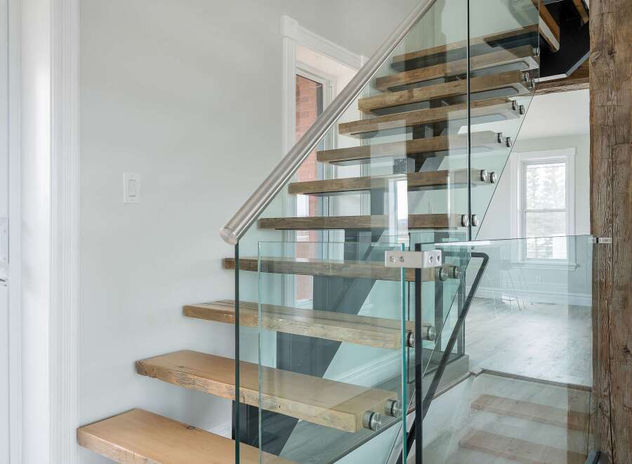 This stunning property boasts a modern staircase with glass railings and wooden steps, creating a seamless blend of contemporary design and natural elements.