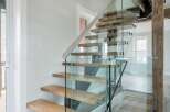 This stunning property boasts a modern staircase with glass railings and wooden steps, creating a seamless blend of contemporary design and natural elements.