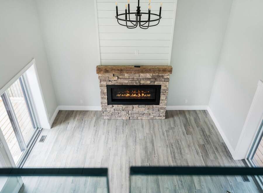 This stunning living room boasts a cozy fireplace with a stone facade and a rustic wooden mantel, creating a warm and inviting atmosphere.