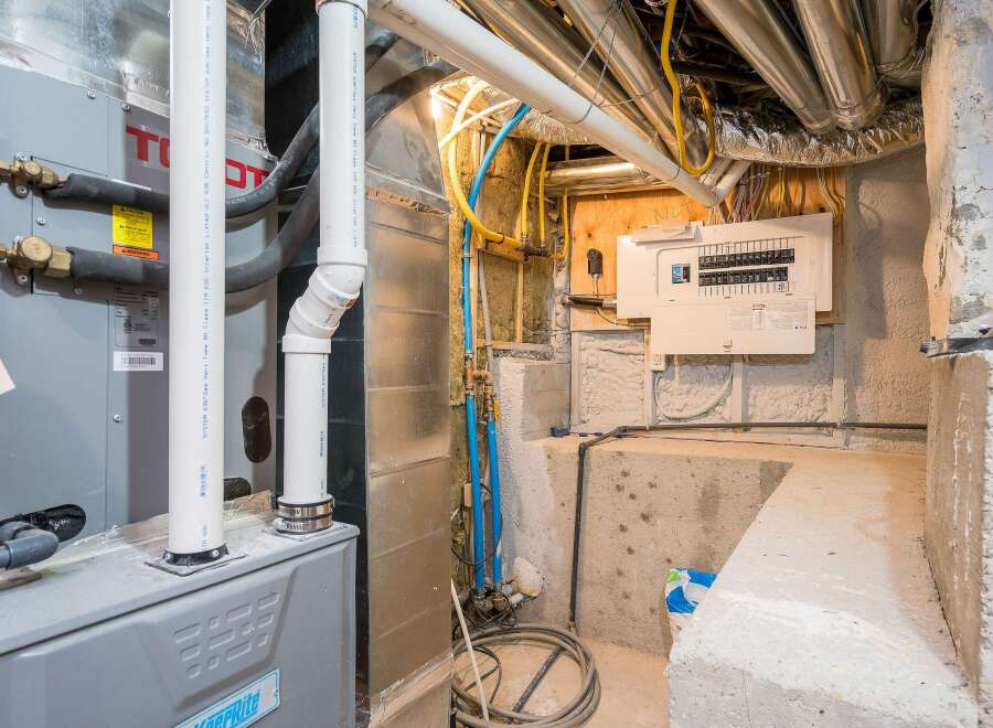 Explore the hidden infrastructure of this property, showcasing a well-maintained furnace and electrical panel.