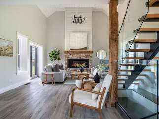 Step into luxury with this stunning living space, featuring a cozy fireplace and a modern staircase.