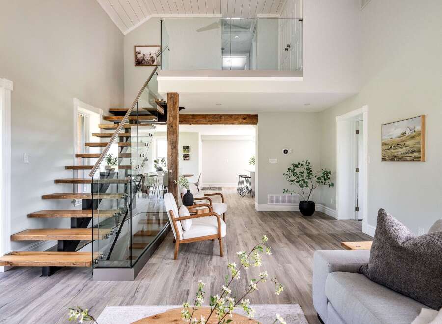 Step into luxury with this stunning property featuring a modern staircase with glass railings and wooden steps.