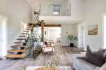 Step into luxury with this stunning property featuring a modern staircase with glass railings and wooden steps.