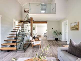 Step into luxury with this stunning property featuring a modern staircase with glass railings and wooden steps.