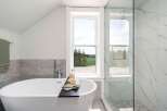 Indulge in the luxury of this stunning bathroom, featuring a sleek, modern soaking tub.