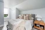 This serene bedroom offers a tranquil retreat with its soft color palette and natural light.
