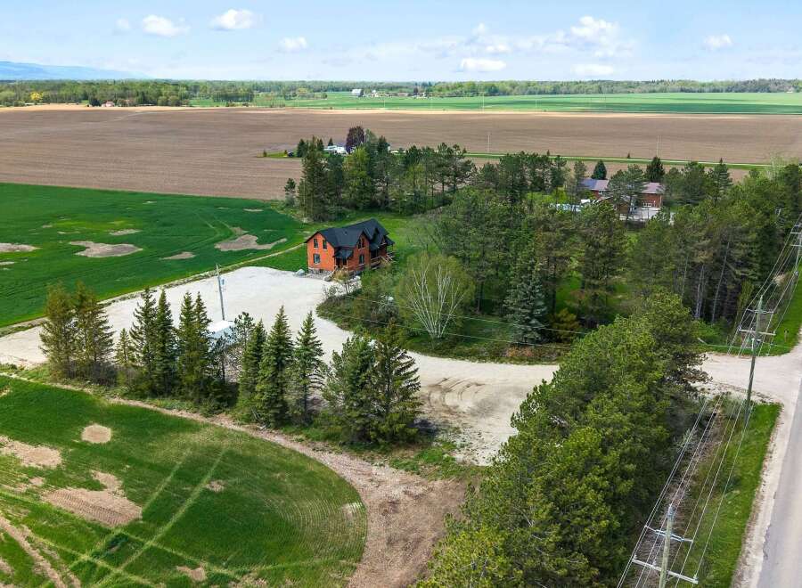 Discover this stunning property featuring a charming house nestled amidst lush greenery and expansive fields.