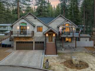 This stunning property boasts a rustic charm with its wooden exterior and stone accents, nestled in a serene, wooded setting.