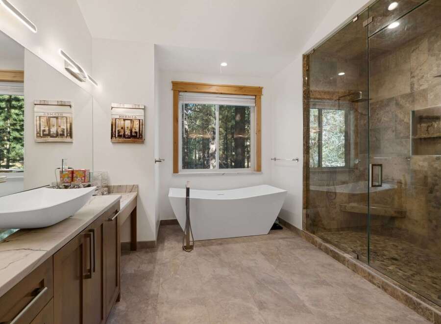 This luxurious bathroom boasts a modern design with a freestanding bathtub, a spacious glass-enclosed shower, and a stylish vanity.