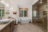 This luxurious bathroom boasts a modern design with a freestanding bathtub, a spacious glass-enclosed shower, and a stylish vanity.