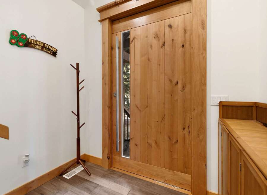 Step into this inviting entryway, showcasing a stunning wooden door with a modern glass panel.