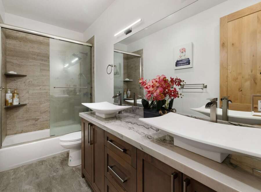 This stunning bathroom features a modern design with a sleek vanity and two stylish sinks.