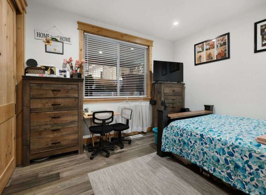 This cozy bedroom features a rustic wooden dresser and a comfortable bed with a floral patterned comforter.