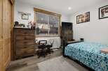 This cozy bedroom features a rustic wooden dresser and a comfortable bed with a floral patterned comforter.