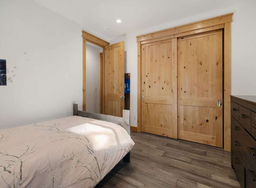 Discover the charm of this inviting bedroom, featuring beautiful wooden doors and a cozy bed.