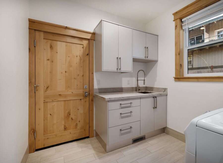This stunning laundry room boasts a modern design with sleek cabinetry and a convenient sink area.