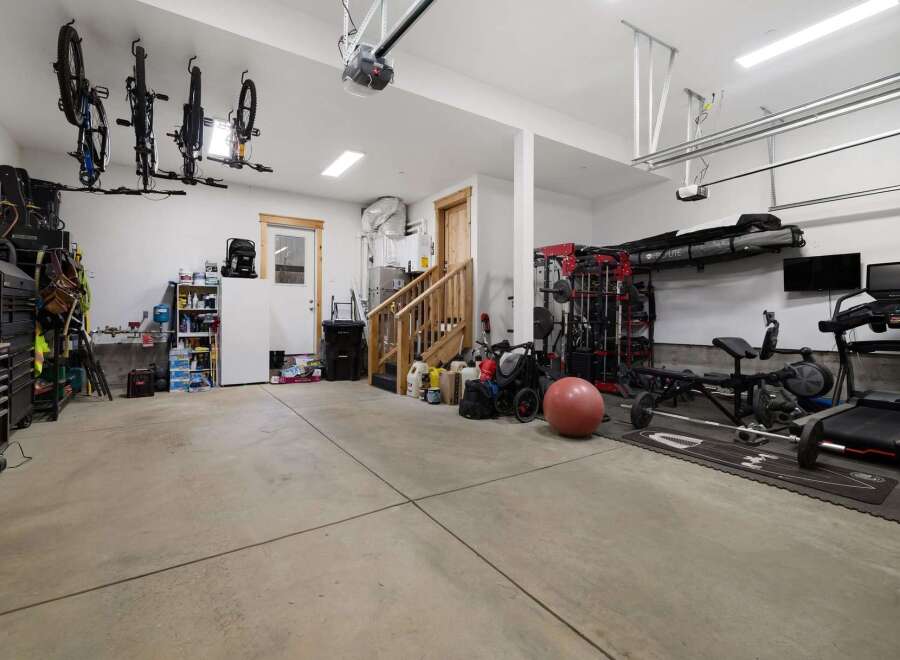 This spacious garage offers ample room for vehicles and storage, complete with a dedicated home gym area.