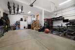 This spacious garage offers ample room for vehicles and storage, complete with a dedicated home gym area.