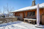 This charming wooden cabin offers a serene escape with its snow-covered surroundings and inviting outdoor space.
