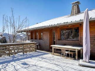 This charming wooden cabin offers a serene escape with its snow-covered surroundings and inviting outdoor space.