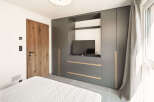 This modern bedroom boasts a sleek, built-in wardrobe with integrated storage and a dedicated TV area, perfect for maximizing space.
