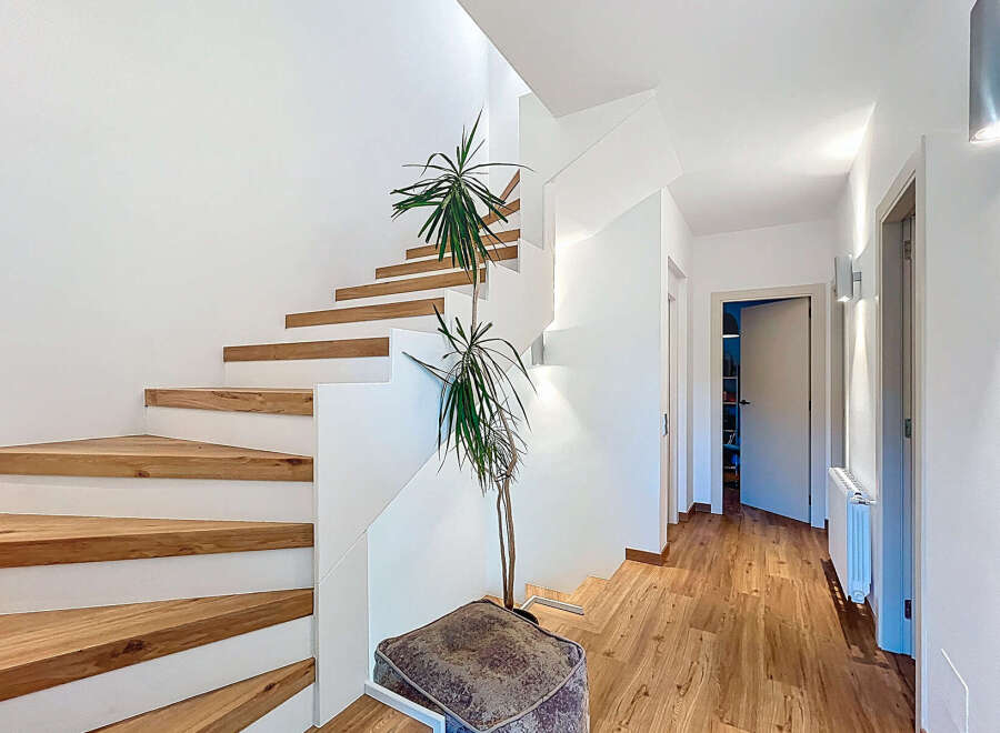 This stunning property features a modern staircase with wooden steps and white risers, creating a sleek and inviting entryway.