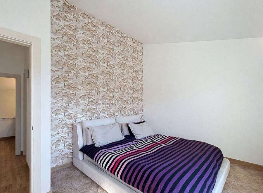 This stylish bedroom features a modern design with a unique wallpaper accent wall.
