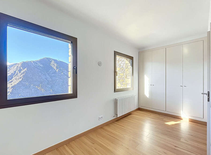 This bright and airy room features stunning mountain views through large windows, offering a serene and picturesque setting.