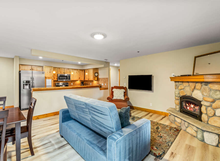 Cozy up in this charming living space, complete with a stone fireplace and a comfortable sofa.