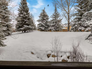 Experience the serene beauty of winter from this property, surrounded by snow-covered evergreen trees and a tranquil landscape.