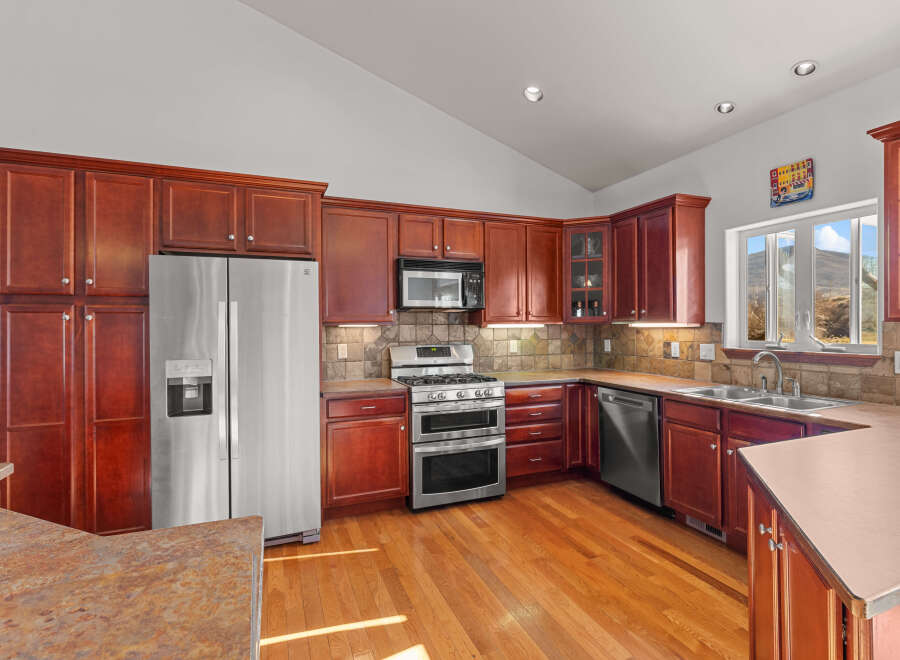 This stunning kitchen boasts rich, dark wood cabinetry and gleaming stainless steel appliances, creating a warm and inviting atmosphere.