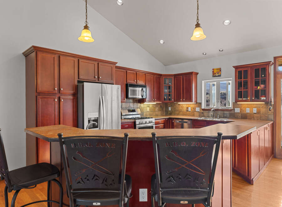 This stunning kitchen boasts rich wood cabinetry, stainless steel appliances, and a stylish breakfast bar.