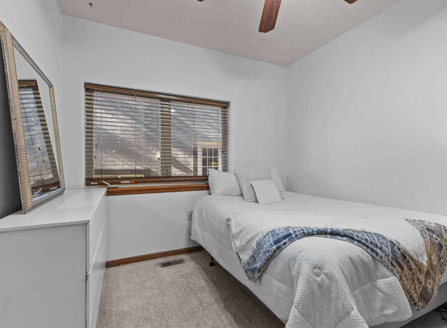 This cozy bedroom features a comfortable bed with a stylish blue and white blanket, perfect for a relaxing night's sleep.